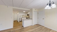 Located at 324 Washington St in Wellesley Hills, MA, this 2-bedroom, 2-bathroom residence offers a thoughtfully designed single-floor layout with a clean, updated aesthetic throughout. The open living room is bright and welcoming, featuring light hardwood-style flooring, soft cream-toned walls, and a glass-paneled door that fills the space with natural light and provides outdoor views. A chandelier adds a subtle decorative touch to the room's airy ambiance. The kitchen is well-appointed with crisp white shaker cabinetry, granite-look countertops, and a full suite of stainless steel appliances including a French door refrigerator, electric range, over-the-range microwave, and dishwasher. Hardwood-style flooring continues seamlessly through the kitchen and common areas. Both bedrooms offer comfortable proportions, plush neutral carpeting, and windows that bring in natural light. The spacious primary bedroom provides ample room for a full furniture arrangement. Both bathrooms feature tub/shower combinations with accessibility-focused grab bars and chrome fixtures, set against light hardwood-style floors and cream walls. The residence combines modern finishes with practical, accessibility-conscious design throughout.