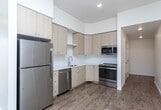 Located at 13450 W Baldcypress St in Boise, Idaho, this single-floor, 3-bedroom, 2-bathroom home offers a clean, modern design throughout. The layout is well-organized, with hallways connecting the living areas and bedrooms efficiently.

The kitchen is outfitted with light natural wood cabinetry extending to the ceiling, white quartz countertops, a classic subway tile backsplash, and stainless steel appliances including a dishwasher and range. Warm hardwood-style flooring runs throughout the main living and kitchen areas, adding continuity and a welcoming feel.

The living area is bright and open, with large windows fitted with horizontal blinds that frame views of the surrounding Boise neighborhood, filling the space with natural light. The bedrooms feature plush neutral carpet and individual windows that let in ample daylight with pleasant outdoor views.

Both bathrooms are finished in a crisp, clean style, featuring tub-shower combinations with white tile surrounds, brushed nickel fixtures and grab bars, light wood vanities, and the same hardwood-style flooring found throughout the rest of the home. Interior hallways with white walls and modern lever-style door hardware complete the tidy, functional aesthetic of this well-appointed Boise residence.