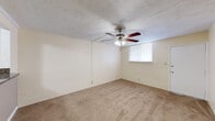 Located at 2206 Heather Ln in Louisville, KY, this single-floor, one-bedroom, one-bathroom unit offers a compact and functional layout with a straightforward design. The space is constructed with painted concrete block walls throughout, giving it a sturdy, solid feel, while tan carpet flooring runs through the main living areas and bedroom.

The living room is an open, carpeted space featuring a ceiling fan with light fixture and a window that allows natural light in. A pass-through counter connects the living room to the kitchen, which includes white cabinetry and a dark countertop, making the layout feel cohesive and efficient.

The bedroom is a comfortable, well-proportioned room with its own ceiling fan, a window with blinds, a wall-mounted AC unit, and a louvered closet door providing convenient storage. The room's painted block walls are accented with a soft sage-green tone near the window wall.

The bathroom is a clean, neatly finished space featuring floor-to-ceiling beige-toned tile surrounding a full tub and shower combo, a white vanity with brushed nickel hardware, a large mirror, and tiled flooring. The unit also includes a hallway and four closets, offering ample storage throughout. A textured ceiling is present in the living and bedroom areas, completing the utilitarian yet livable character of this Louisville unit.