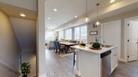 This thoughtfully designed 3-floor home offers a seamless blend of comfort and modern style throughout its well-organized layout. The main living area showcases an open-concept floor plan where the kitchen, dining, and living spaces flow together effortlessly. Large windows flood the space with natural light and provide neighborhood views, while wood-look flooring and recessed lighting lend a clean, contemporary feel. The kitchen features white cabinetry, light countertops, stainless steel appliances including a dishwasher and range, a tiled backsplash, and a central island with pendant lighting — ideal for both cooking and casual entertaining. The dining area accommodates a full table and connects directly to a comfortable living room with a ceiling fan and staircase access. Bedrooms are carpeted and well-sized, each with windows offering natural light. The primary bedroom includes a stylish sliding barn door leading to an en-suite bathroom with a glass-enclosed shower. A secondary full bathroom features a soaking tub-shower combination with white tile surround and wood-look flooring. A dedicated laundry room with stacked washer and dryer, cabinetry, and a utility counter adds everyday convenience. The overall ambiance is warm, neutral, and move-in ready.