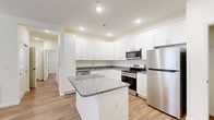 This single-story, 2-bedroom, 2-bathroom home offers a thoughtfully designed layout that maximizes functionality and comfort. The open-concept kitchen and living area serves as the heart of the home, featuring crisp white shaker cabinetry extending to the ceiling, granite countertops, and a central island that provides additional prep and dining space. Stainless steel appliances — including a refrigerator, range, and over-the-range microwave — complete the kitchen. Recessed lighting and wood-look plank flooring run throughout, lending warmth and continuity to the space. The living area benefits from natural light through a large window and exterior door, and is finished with a ceiling fan overhead. Both bedrooms are well-sized, with the primary bedroom offering a generous walk-in closet equipped with wire shelving. The bathrooms mirror the kitchen's aesthetic, showcasing granite-topped white vanities and tub-shower combinations with tile surrounds. Additional features include a dedicated laundry area, pantry, utility room, and multiple closets for ample storage. The neutral color palette and clean finishes give the home a modern, move-in-ready appeal throughout.