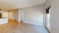 Located at 5042 Linbar Dr in Nashville, TN, this well-appointed one-bedroom, one-bathroom unit offers a thoughtfully designed layout with contemporary finishes throughout. The open-concept kitchen and living area serves as the heart of the home, featuring light wood-style flooring, recessed lighting, and a peninsula with dark quartz countertops that provides additional prep and seating space. The kitchen is outfitted with white shaker cabinetry, stainless steel appliances including a refrigerator, electric range, and microwave, offering both style and functionality. The living area is bright and airy, benefiting from floor-to-ceiling windows and French doors that open to a balcony, allowing abundant natural light and outdoor views. The bedroom is carpeted for comfort and includes a wall-mounted mini-split HVAC unit, along with a large window that continues the theme of natural light. A dedicated closet with built-in wire shelving provides practical storage. The bathroom is finished with a white vanity, dark quartz countertop, a large mirror, and wood-style flooring, with a frosted glass door leading to the shower area. Neutral gray walls throughout the unit create a clean, modern aesthetic.