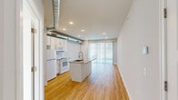 This 1-bedroom, 1-bathroom unit in Clawson, Michigan offers a smart, efficient layout that maximizes every square foot of living space. The open-concept main area seamlessly connects the kitchen and living space, anchored by warm hardwood flooring that runs throughout. The kitchen is a standout feature, showcasing a central island with a granite countertop and an undermount sink with a modern pull-down faucet. White shaker-style cabinetry, a subway tile backsplash, and white appliances — including a refrigerator, electric range, and microwave — complete the clean, cohesive look. An exposed metallic ductwork element adds an industrial design accent overhead. A sliding glass door floods the living area with natural light and provides access to the outdoors. The bedroom is a comfortable, carpet-floored retreat with a large window that brings in abundant natural light and offers outdoor views. A closet provides practical storage. The bathroom features a clean, white tub-shower combination with built-in shelving and modern chrome fixtures. Neutral tones and recessed lighting throughout the unit contribute to a bright, airy ambiance well-suited for comfortable everyday living.