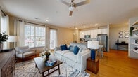 This single-floor residence offers a thoughtfully designed open-concept layout that seamlessly connects the living, dining, and kitchen areas. The living room is generously proportioned, featuring elevated ceilings with a ceiling fan, warm hardwood flooring, and large windows that invite abundant natural light. A sliding glass door provides outdoor views and adds to the airy, welcoming atmosphere of the space.

The kitchen is both functional and stylish, outfitted with crisp white cabinetry, granite countertops, a classic white subway tile backsplash, and stainless steel appliances including a refrigerator, range, and microwave. A peninsula with seating serves as a natural divider between the kitchen and living area, making it ideal for casual dining or entertaining. Pendant lighting accents the space above.

A secondary living or flex room offers additional space and features hardwood floors, a ceiling fan, and a large window, providing versatility for use as a den, home office, or guest space.

The bedroom is a tranquil retreat with plush carpet, a ceiling fan, and generous windows dressed with layered curtains that filter soft natural light. It connects directly to a well-appointed en-suite bathroom featuring granite countertops, white cabinetry, and hardwood flooring. The overall design throughout the space is cohesive, clean, and modern.