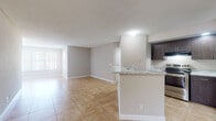 Located at 672 Siesta Key Cir in Deerfield Beach, Florida, this single-floor residence offers a clean, functional layout with a cohesive neutral color palette throughout. The open-concept living and dining area is finished with large-format ceramic tile flooring, providing a bright and airy atmosphere enhanced by natural light from sizable windows with vertical blinds. The kitchen is positioned adjacent to the living space and features dark espresso cabinetry, stainless steel appliances including a range and refrigerator, and a marble-patterned countertop that extends to a peninsula breakfast bar — ideal for casual dining or additional prep space. The bedrooms are carpeted in a warm, neutral tone, offering a comfortable contrast to the tiled common areas, and each includes a window that allows in natural light. The bathroom is well-appointed with a dark wood vanity, marble-style countertop, an undermount sink, and a tiled tub-shower combination. A laundry area is also accessible within the unit. Textured ceilings are consistent throughout the home. The overall design is practical and move-in ready, with a clean, contemporary aesthetic suited for everyday living in South Florida.