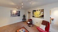 This single-floor, two-bedroom, one-bathroom unit offers a practical and well-organized layout designed for comfortable everyday living. The living room serves as the heart of the home, featuring plush carpeting, a wall-mounted flat-screen TV, and a track lighting system that provides flexible illumination. A large window with vertical blinds allows natural light to fill the space, complemented by a wall-mounted air conditioning unit for year-round comfort.

The galley-style kitchen is efficiently designed with warm wood cabinetry, dark granite-style countertops, a double stainless steel sink, and black appliances including a refrigerator, electric range, and microwave. Tile flooring and ample cabinet storage above and below the counters make this kitchen both functional and well-appointed.

A carpeted hallway with track lighting connects the main living area to the two bedrooms. Both bedrooms feature neutral walls, soft carpeting, and windows with vertical blinds that provide natural light and privacy. One bedroom is more generously sized with multiple windows, while the second offers a cozy, focused layout well-suited as a guest room or home office. The overall ambiance of the unit is clean, bright, and move-in ready.