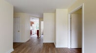This single-floor unit offers a clean, functional layout with a warm and inviting aesthetic throughout. Durable hardwood-style flooring flows continuously across the main living areas, complemented by soft cream-toned walls that lend a bright, airy feel to every room.

The open living area provides generous space and connects seamlessly to the rest of the unit. Multiple windows throughout the space invite abundant natural light and offer pleasant views of the surrounding greenery and outdoor scenery. Ceiling fans are present in the bedrooms, adding both comfort and airflow.

The kitchen is well-equipped with rich, deep-toned wood cabinetry, light stone-finish countertops, and white appliances including a range, over-the-range microwave, and dishwasher. A large window above the counter area frames a leafy outdoor view, making the kitchen feel open and connected to the outside.

The bedrooms are generously proportioned, each featuring hardwood-style flooring, ample natural light from well-placed windows, and baseboard heating. One bedroom includes a sliding mirrored closet door, adding both storage and visual depth.

The bathroom features a full soaking tub with a tiled surround in warm neutral tones, paired with a white vanity and a combination shower, rounding out this comfortable and practical living space.