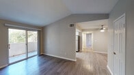 This single-floor residence offers a thoughtfully designed layout with a blend of comfort and modern finishes throughout. The open living area makes an immediate impression with its vaulted ceilings that lend a sense of spaciousness and airiness. Durable hardwood-style flooring flows through the main living spaces, complemented by neutral gray tones on the walls that create a clean, contemporary aesthetic. Sliding glass doors in the living room open to a private outdoor space, inviting abundant natural light and easy access to the exterior. The galley-style kitchen is well-equipped with crisp white shaker cabinetry, light countertops, stainless steel appliances including a refrigerator, electric range, microwave, and dishwasher, as well as a window that brightens the workspace. The bedrooms feature plush carpeting underfoot and ceiling fans for added comfort, with closet storage included. A dedicated entry area with hardwood-style flooring and access doors provides a practical transition into the home. The bathroom is fitted with a full tub-shower combination, complete with a curved curtain rod and grab bar, finished with coordinating hardwood-style flooring. Overall, the space presents a clean, move-in ready environment with consistent finishes and a functional flow throughout.