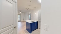 Located on E Ponce de Leon Ave in Decatur, GA, this one-bedroom, one-bathroom unit offers a well-designed, efficient layout across a single floor. The open-concept kitchen serves as a focal point, centered around a striking navy blue island with a white quartz countertop, undermount sink, and pendant lighting overhead. White upper cabinetry, grey tile backsplash, and stainless steel appliances—including a refrigerator, range, and microwave—complete the kitchen. Light wood-style flooring runs through the kitchen and living area, which features a ceiling fan and a glazed exterior door that admits natural light and outdoor views.

The bedroom is carpeted and includes a ceiling fan, a window with outdoor views, and access to a spacious walk-in closet equipped with multi-level wire shelving. The bathroom features a white vanity with quartz countertop, a wood-framed mirror, and a tiled tub-shower combination. A dedicated laundry area accommodates a stacked washer and dryer. The unit's clean, white interior palette and modern finishes create a bright, cohesive aesthetic throughout.