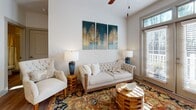 Located at 1100 Monocan Ln in Earlysville, VA, this single-floor residence offers a thoughtfully designed layout with a cohesive blend of comfort and modern finishes. The living room serves as a welcoming centerpiece, featuring elevated ceilings, abundant natural light through large windows, and a ceiling fan overhead — an ideal setting for relaxing or entertaining. Adjacent to the living area, the dining space features a warm wooden table beneath a decorative wall accent, with an open sightline to the living room that enhances the sense of flow. The kitchen is outfitted with light wood cabinetry, granite-look countertops, and black appliances including a range, over-the-range microwave, and refrigerator, all set atop durable wood-look flooring. The bedrooms are carpeted and filled with natural light, with one featuring dual windows, a ceiling fan, and generous proportions, while another includes a wall-mounted television and direct access to a spacious walk-in closet with full wire shelving systems. The bathrooms are finished with granite-topped vanities, wood-look flooring, and a combination tub and shower, offering clean, practical design. The primary bathroom also connects directly to the walk-in closet, adding a practical and elegant touch to the private quarters.