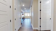 This single-floor space offers a thoughtfully designed layout with a cohesive aesthetic throughout. Wood-look tile flooring runs through the main living and kitchen areas, providing a warm and durable foundation that ties the space together visually.

The kitchen is well-equipped with rich, dark-stained wood cabinetry, granite-look countertops, and a full suite of stainless steel appliances including a range, over-the-range microwave, refrigerator, and dishwasher. Recessed lighting illuminates the workspace efficiently, and crown molding adds a refined finishing touch.

A wide hallway connects the kitchen to the main living area, flanked by white panel doors with black hardware accents. The hallway features built-in cabinetry, providing ample storage. The living area benefits from generous natural light through large windows fitted with dual-shade roller blinds, and a sliding glass door opens to an outdoor balcony or patio enclosed by decorative iron railings. The views extend across an open landscape, giving the space an airy, expansive feel.

The bathroom includes a vanity with granite-look countertops and dark wood cabinetry, wood-look tile flooring, and a combination tub and shower with stone-surround tile walls. A separate carpeted room with a wall-mounted mini-split HVAC unit rounds out the layout, offering a comfortable and climate-controlled space.