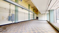 Located at 320 N Huron St in the heart of downtown Toledo, Ohio, this single-floor commercial green space offers a generously open and versatile layout spanning nearly three thousand square feet. The space features a notably open floor plan, making it well-suited for a variety of commercial or community uses. A hallmark of the interior is the classic checkered tile flooring that runs throughout, lending a retro character to the space. The high ceilings add a sense of volume and airiness, while exposed ductwork and industrial-style HVAC components contribute to a raw, functional aesthetic. Large storefront windows along the street-facing facade flood the interior with natural light and provide clear views of the surrounding downtown streetscape, creating a strong visual connection to the urban environment outside. Green-painted structural columns and accents punctuate the cream and yellow walls, adding architectural interest. A raised platform area near the windows adds dimensional variety to the floor plan. Restroom facilities are accessible from within the space, indicated by interior signage. The space is currently in shell condition, presenting an open canvas ideal for buildout tailored to a new tenant's or operator's vision. Its prominent downtown location and expansive, light-filled interior make it a compelling opportunity for retail, hospitality, or community-oriented use.