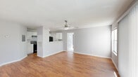 Located at 4700 Walden Cir in Orlando, Florida, this single-floor home offers a clean, functional layout with a neutral color palette throughout. The open living and dining area is finished with warm hardwood-style flooring and features a ceiling fan overhead, creating a bright and airy atmosphere. A pass-through counter connects the living space to the kitchen, which is equipped with white cabinetry, light stone-look countertops, a stainless steel sink, and black appliances including a refrigerator and range. A secondary living area or flex room opens to the outdoors through a sliding glass door fitted with vertical blinds, accompanied by a window that invites natural light. The bedrooms are carpeted for comfort, each featuring neutral walls, windows with blinds, and ample space. The two bathrooms are finished with hardwood-style flooring, white tub-shower combinations, and clean white fixtures. The primary bathroom includes a vanity with a stone-look countertop and a louvered closet door. Throughout the home, consistent light gray walls and white trim create a cohesive, move-in-ready aesthetic well-suited to the sunny Orlando climate.