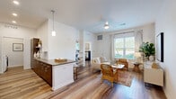 Located in Orlando's Lake Nona area, this well-appointed 2-bedroom, 2-bathroom single-floor residence offers a thoughtfully designed open-concept layout. Wide-plank wood-look flooring flows seamlessly throughout, lending warmth and visual continuity to every room.

The combined kitchen and living area serves as the heart of the home. The kitchen features dark wood cabinetry with sleek hardware, stone-look countertops, stainless steel appliances, recessed lighting, and a peninsula island with pendant lighting—ideal for casual dining or entertaining. The living area is bathed in natural light from large windows with outdoor greenery views, and is complemented by a ceiling fan overhead.

The primary bedroom is a comfortable retreat with a bright window framing outdoor views, while the second bedroom offers a similarly serene atmosphere. Each bedroom benefits from dedicated closet space. Both bathrooms are finished with warm wood-tone vanities and stone countertops; one features a full soaking tub with white tile surround, while the other includes an accessible walk-in shower with grab bars.

A dedicated in-unit laundry room with full-size washer and dryer adds everyday convenience, and a utility room provides additional storage. The clean white walls, consistent flooring, and modern finishes throughout give the space a bright, cohesive, and contemporary feel.