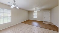 Located at 20879 Red Cedar Dr in Harrah, Oklahoma, this single-story home offers a practical and comfortable layout across its one bedroom and one bathroom. The open-concept living and dining area greets you with a mix of light tile flooring and warm wood-look laminate, complemented by ceiling fans with integrated lighting and a decorative chandelier. Natural light filters in through slatted blinds, creating a bright and welcoming atmosphere throughout.

The kitchen is a standout feature, showcasing rich, warm-toned wood cabinetry, granite-look countertops, and a wraparound layout that maximizes counter and storage space. A peninsula breakfast bar opens the kitchen toward the living area, enhancing the sense of flow. White appliances, including a range and refrigerator, complete the functional setup.

The bedroom offers plush carpeting underfoot, a ceiling fan, and a window with natural light, along with two doors providing access to both a closet and the hallway. The bathroom is cleanly appointed with matching wood cabinetry, granite-look countertops, tile flooring, and accessibility-friendly grab bars. The attached garage features an automatic opener and a concrete floor, providing secure parking and additional storage space.