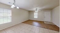 Located at 20879 Red Cedar Dr in Harrah, Oklahoma, this single-story home offers a practical and comfortable layout across its one bedroom and one bathroom. The open-concept living and dining area greets you with a mix of light tile flooring and warm wood-look laminate, complemented by ceiling fans with integrated lighting and a decorative chandelier. Natural light filters in through slatted blinds, creating a bright and welcoming atmosphere throughout.

The kitchen is a standout feature, showcasing rich, warm-toned wood cabinetry, granite-look countertops, and a wraparound layout that maximizes counter and storage space. A peninsula breakfast bar opens the kitchen toward the living area, enhancing the sense of flow. White appliances, including a range and refrigerator, complete the functional setup.

The bedroom offers plush carpeting underfoot, a ceiling fan, and a window with natural light, along with two doors providing access to both a closet and the hallway. The bathroom is cleanly appointed with matching wood cabinetry, granite-look countertops, tile flooring, and accessibility-friendly grab bars. The attached garage features an automatic opener and a concrete floor, providing secure parking and additional storage space.