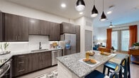 Located at 8157 Ederville Rd in Fort Worth, TX, this thoughtfully designed one-bedroom, one-bathroom residence offers a well-appointed layout across a single floor. The kitchen is a standout feature, showcasing rich dark wood cabinetry, granite countertops with a subway tile backsplash, stainless steel appliances, and a central island with pendant lighting and bar seating — ideal for both cooking and casual dining. Light wood-tone flooring runs throughout, lending warmth and continuity to the space. The living room is bright and welcoming, featuring a ceiling fan, tall ceilings, and French doors dressed in bold rust-orange curtains that open to a private patio overlooking a landscaped courtyard. The bedroom offers a comfortable retreat with a large window that draws in natural light, complemented by stylish window treatments. The bathroom includes a granite-topped vanity with dark cabinetry, a soaking tub with shower, and clean, modern finishes. A hallway connects the rooms efficiently, and a dedicated closet provides practical storage. The private patio adds valuable outdoor living space with a railed enclosure and green surroundings, completing this well-rounded urban residence.