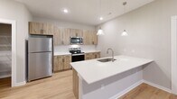 Located at Chelsea Place Way in Knoxville, Tennessee, this well-appointed 2-bedroom, 2-bathroom single-floor residence offers a thoughtfully designed layout with modern finishes throughout. The open-concept kitchen and living area serves as the heart of the home, featuring light wood-tone cabinetry with matte black hardware, white quartz countertops, stainless steel appliances including an electric range and built-in microwave, and light hardwood-style flooring that extends throughout the main living spaces. A dedicated pantry provides additional storage convenience adjacent to the kitchen. The living area is bright and airy, with a ceiling fan, large windows, and sliding glass doors that open onto a private balcony with outdoor views of the surrounding greenery. Both bedrooms are carpeted and equipped with ceiling fans, offering a comfortable retreat. The generously sized primary bedroom includes a walk-in closet with wire shelving. The bathrooms feature the same warm wood-tone cabinetry and quartz countertops seen in the kitchen, maintaining a cohesive aesthetic. A dedicated laundry room with a full-size washer and dryer adds everyday practicality. The entrance hallway leads smoothly into the main living spaces, creating a welcoming flow throughout this clean, contemporary residence.
