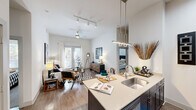Located in Austin, TX, this well-appointed 2-bedroom, 2-bathroom residence offers a thoughtfully designed single-floor layout with a clean, modern aesthetic throughout. The open-concept kitchen and living area serves as the heart of the home, where a large center island with a double sink and light quartz countertops anchors the space. Dark cabinetry pairs with stainless steel appliances, including a full-size refrigerator and range, while subway tile backsplash adds a contemporary touch. Wood-style flooring flows throughout the main living areas, complemented by track lighting and a modern pendant fixture above the island. The living room benefits from elevated ceilings and generous natural light streaming through French doors, creating an airy, open ambiance. Both bedrooms are comfortably sized, featuring plush carpeting, tall ceilings, and dedicated closets with built-in shelving and hanging rods. Each bathroom mirrors the home's modern palette, featuring tiled tub-shower combinations, wood-style flooring, and vanities with dark cabinetry. A connecting hallway links all rooms efficiently. The overall design balances contemporary finishes with a warm, livable feel throughout every room.