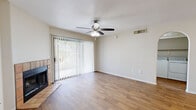Located at 7300 N Mona Lisa Rd in Tucson, AZ, this one-bedroom, two-bathroom residence offers a well-organized single-floor layout designed for comfortable everyday living. The living room serves as the heart of the home, featuring warm wood-look flooring, a ceiling fan with light fixture, and a tile-surround fireplace that adds a classic focal point. A full-width sliding glass door floods the space with natural light and provides direct access to an outdoor patio area with views of the surrounding landscape. An arched opening connects the living area to a dedicated laundry space, adding functional convenience. The galley-style kitchen is efficiently designed with light wood cabinetry lining both sides, ample counter space, a double-basin sink, and white appliances including an electric range and refrigerator. A window at the end of the kitchen brings in additional natural light. The spacious primary bedroom includes its own ceiling fan, a window with vertical blinds, and hardwood-style flooring. The primary bathroom features a single-sink vanity with built-in cabinetry and access to a dedicated closet. A second full bathroom offers a tub-shower combination. Neutral tones and wood-look flooring throughout create a cohesive, clean aesthetic across the entire unit.