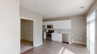 Located at 2255 Wisconsin Ave NW in the vibrant Georgetown neighborhood of Washington, DC, this apartment offers a well-designed single-floor layout with a clean, modern aesthetic throughout. The open-concept living and kitchen area is anchored by warm hardwood-style flooring and neutral gray-toned walls, creating a bright and cohesive atmosphere. Large sliding glass doors in the living area are dressed with vertical blinds, allowing generous natural light to fill the space while offering views of lush greenery outside. The kitchen features sleek, floor-to-ceiling white cabinetry, light countertops, and a full suite of stainless steel appliances including a refrigerator, electric range, built-in microwave, and dishwasher — combining style with everyday functionality. Recessed lighting throughout adds a polished finish. The bedroom is carpeted for comfort and maintains the unit's clean, minimalist character with crisp white walls. The bathroom is finished with large-format light tile flooring, white subway tile surrounding the tub-shower combo, and a modern floating vanity with an integrated sink. This residence presents a contemporary urban living experience in one of DC's most sought-after neighborhoods.
