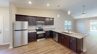 Located at 3062 12th Ave SE in Hickory, NC, this well-appointed single-story home offers 2 bedrooms and 2 full bathrooms within a thoughtfully designed floor plan. The open-concept kitchen and living area serves as the heart of the home, featuring granite countertops with an undermount sink, dark cabinetry, recessed lighting, and hardwood-style flooring that extends throughout the main living spaces. The living room benefits from vaulted ceilings, a ceiling fan, and sliding glass doors that invite natural light and provide views of the backyard greenery. Both bedrooms are carpeted and include ceiling fans, with the primary bedroom offering a generous layout and its own closet. The primary bathroom is equipped with a dual-sink granite vanity, dark cabinetry, a walk-in shower, and wood-look flooring. The secondary bathroom mirrors this quality with a matching vanity and a shower-tub combo. Two closets provide ample storage throughout the home. The attached garage features a panel door with upper windows, an automatic opener, recessed lighting, and direct interior access — completing this clean, move-in-ready home.