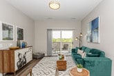 This thoughtfully designed single-floor residence offers a seamless blend of modern aesthetics and functional living across its open-concept layout. The kitchen serves as a central hub of the space, showcasing dark espresso cabinetry, a classic white subway tile backsplash, stainless steel appliances including a refrigerator, microwave, and dishwasher, and a crisp white countertop island with bar seating — ideal for casual dining or entertaining. Wood-look flooring flows throughout the main living areas, adding warmth and continuity to the space. The living area is generously proportioned, offering ample room for comfortable seating and a relaxed, inviting atmosphere. The two bedrooms are carpeted for comfort, each providing a calm retreat with neutral wall tones and natural light from large windows. One bedroom offers a direct view into the kitchen area, reinforcing the open and connected nature of the floor plan. The bathroom is finished with a wide-format vanity featuring dark cabinetry, a white countertop, a large mirror, and wood-look flooring that ties seamlessly into the rest of the home. Open shelving and recessed lighting throughout the space contribute to its clean, contemporary character.