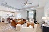 Located at 1702 Rocky River Road in Charlotte, NC, this single-story home offers a thoughtfully designed open-concept floor plan that maximizes every square foot. The living room serves as the heart of the home, featuring a tray ceiling with a ceiling fan, warm hardwood-style flooring, and large windows dressed with elegant drapes that invite abundant natural light. The space flows seamlessly into the kitchen, which is outfitted with white shaker cabinetry, a subway tile backsplash, stainless steel appliances, and a central island with bar seating — perfect for casual dining. A sliding glass door connects the kitchen to an outdoor patio area. The primary bedroom is a comfortable retreat with multiple windows and ample natural light. The second bedroom features a large window with outdoor views, providing a bright and versatile space. Four bathrooms serve the home, including one with a framed glass-enclosed walk-in shower. Hardwood-style flooring runs throughout, complemented by neutral gray-toned walls that lend a clean, modern aesthetic. An entrance foyer with a decorative mirror, dedicated closet, and connecting hallways round out the practical layout of this move-in-ready Charlotte home.