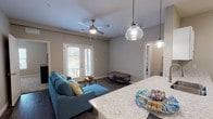 This single-floor residence at Villas of Jeffersonville is thoughtfully designed with a modern aesthetic and practical layout. The open-concept living area features durable wood-look flooring, neutral gray walls, and a ceiling fan, with French doors that invite natural light and provide outdoor access. A granite-topped kitchen island with pendant lighting bridges the living space and the galley-style kitchen, which is equipped with white shaker cabinets, granite countertops, stainless steel appliances — including a range, microwave, dishwasher, and refrigerator — all set atop matching wood-look flooring. Adjacent to the kitchen is a dedicated dining area with hardwood-style floors and a flush-mount ceiling light, ideal for everyday meals or entertaining. The bedrooms offer plush carpeting, ceiling fans, and ample natural light through blinds-covered windows, with closet space conveniently built in. The bathrooms are finished with white vanity cabinetry, granite countertops, and wood-look tile flooring; one features a walk-in closet with wire shelving, while the other includes a full tub-shower combination. Throughout, the consistent warm-toned palette and quality finishes create a cohesive, comfortable living environment.