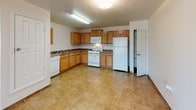 This single-floor residence offers a functional and comfortable layout designed for everyday living. The kitchen is a standout feature, equipped with warm honey-toned oak cabinetry, dark-speckled laminate countertops, and a full suite of white appliances including a gas range, built-in microwave, dishwasher, and refrigerator. A deep double-basin sink and generous counter space make this kitchen both practical and efficient. The flooring throughout the kitchen features neutral stone-look tile, which also carries into the entryway and bathrooms. The living area is open and inviting, highlighted by a ceiling fan with light fixture and a sliding glass door fitted with vertical blinds that allow abundant natural light and outdoor access. The carpeted bedrooms each feature ceiling fans or overhead lighting, natural window light, and sliding or panel-style closets offering ample storage space. The bathrooms are finished with warm terracotta-toned tile flooring and large-format tile surrounding the soaking tub and shower combination. Each bathroom includes a vanity with storage cabinetry above. The overall design is clean, neutral, and move-in ready, with a consistent warm color palette throughout.