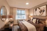 Located at 2052 Morris Ave in Union, NJ, this thoughtfully designed single-floor residence combines contemporary finishes with a warm, inviting atmosphere throughout. The open-concept kitchen is a true highlight, outfitted with gray shaker-style cabinetry, quartz countertops, a textured tile backsplash, and a full suite of stainless steel appliances including a gas range and built-in microwave. A center island with pendant lighting provides additional prep space and casual seating, making it ideal for both cooking and entertaining. The living area is bright and welcoming, featuring large windows that invite natural light, hardwood-style flooring, and a neutral color palette that creates a clean, modern aesthetic. A dedicated dining nook flows naturally from the living space, offering a cohesive open layout. The bedroom is a serene retreat, with ample space, large windows dressed in sheer curtains, and the same warm flooring that carries throughout the unit. The bathroom is finished with large-format tile flooring and a full tub-shower combination with clean, white tile surround. Neutral tones and recessed lighting are consistent throughout, contributing to a refined and comfortable living environment well-suited for everyday living.