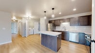 Located at 4216 N Lightning Dr in Appleton, WI, this single-floor, 2-bedroom, 2-bathroom home offers a thoughtfully designed layout with modern finishes throughout. The open-concept kitchen and living area serves as the heart of the home, showcasing dark espresso cabinetry, a stainless steel appliance suite including a refrigerator, range, and microwave, a subway tile backsplash, and a central island with a light marble-style countertop illuminated by stylish pendant lighting. Light hardwood-style flooring flows through the main living areas, lending warmth and continuity. The spacious primary bedroom features soft carpeting, a ceiling fan, and a window for natural light, while the second bedroom is equally comfortable with plush carpet and a clean, neutral palette. Both bathrooms are finished with dark wood vanities, white countertops, round mirrors, and light flooring for a cohesive aesthetic. A dedicated laundry area with side-by-side washer and dryer adds everyday convenience. Four closets provide generous storage throughout. The attached garage offers ample space for vehicles and additional storage. A sliding glass door in the living area provides outdoor access and fills the space with natural light, completing this functional and modern home.