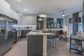 Located at 900 Battery Ave SE in Atlanta, Georgia, this single-floor residence offers a thoughtfully designed interior with modern finishes throughout. The open-concept kitchen is a standout feature, showcasing two-tone cabinetry with dark lower cabinets and crisp white upper cabinets, quartz countertops, a subway tile backsplash with under-cabinet lighting, and a full suite of stainless steel appliances. A spacious island with a double sink and pendant lighting serves as both a functional workspace and a casual dining area, flowing seamlessly into the living space. The living area is bright and inviting, with hardwood-style flooring, floor-to-ceiling draping, and direct access to an outdoor patio through a glass door. The bedroom is a refined retreat, highlighted by a dramatic abstract mural accent wall, plush carpeting, natural light from large windows, and elegant drapery. The en-suite bathroom features clean white cabinetry, a wide vanity mirror, and wood-look flooring that leads directly into a well-organized walk-in closet with wire shelving. A dedicated laundry area with a stacked washer and dryer adds everyday convenience. The overall aesthetic is contemporary and cohesive, combining functionality with sophisticated design.