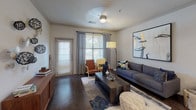 This single-story Houston residence offers a thoughtfully designed open-concept layout that seamlessly connects the main living areas. The kitchen serves as a central hub, showcasing rich dark cherry wood cabinetry extending to the ceiling, dark granite countertops, stainless steel appliances including a refrigerator, range, and microwave, and a curved peninsula with a double basin sink. Track lighting illuminates the workspace, complementing the recessed ceiling lights throughout. The living room features rich hardwood-style flooring, large windows with blinds and curtains that invite natural light, crown molding details, a ceiling fan, and direct access to an exterior door. The bedrooms are carpeted and well-proportioned, each offering good natural light from sizable windows. The primary bathroom includes dark granite countertops atop cherry wood vanity cabinetry, tile flooring, and a walk-in closet. A dedicated laundry area with a full-sized washer and dryer adds everyday convenience. The overall color palette of warm neutrals and crisp whites creates a cohesive, welcoming ambiance throughout the residence.