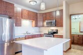 Located at 2400 Parmenter St in Middleton, WI, this one-bedroom, one-bathroom residence offers a well-designed single-floor layout with a thoughtful use of space throughout. Light-toned hardwood-style flooring flows through the main living areas, complementing the warm wood trim accents found consistently throughout the unit.

The kitchen is a standout feature, equipped with rich dark-stained cabinetry reaching toward the ceiling for generous storage, a full suite of stainless steel appliances including a refrigerator, range, microwave, and dishwasher, and a central island with a white quartz countertop and pendant lighting above — ideal for both cooking and casual dining.

The kitchen opens seamlessly into the living room, which benefits from natural light pouring in through a sliding glass door that leads to a private balcony with outdoor views of the surrounding landscape.

The bedroom is a comfortable, well-proportioned space with plush carpeting, a large window providing additional natural light, and direct access to a dedicated closet with built-in shelving for organized storage.

The bathroom is finished with a granite-topped vanity with rich wood cabinetry, a full tub-shower combination, and a large wall mirror. The overall ambiance of the unit is clean, modern, and functional.