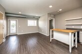 This well-designed single-floor unit offers a thoughtful layout with modern finishes and a neutral color palette throughout. The open-concept kitchen and living area serves as the heart of the space, featuring wood-look plank flooring, recessed lighting, and exposed ductwork that adds an industrial touch. The kitchen is equipped with light wood cabinetry, stainless steel countertops, black appliances including a range, dishwasher, and refrigerator, a single-basin sink, and open floating shelves for additional storage. A mobile butcher block island provides flexible workspace and flows naturally into the open living area.

The bedrooms are carpeted for comfort and each includes access to a walk-in closet outfitted with wire shelving and hanging rods, providing generous storage capacity. The unit features two bathrooms, both finished with classic white hexagonal tile flooring. The primary bathroom includes a wide vanity with a white countertop, a large mirror, and a soaking tub, while the secondary bathroom is compact and functional with its own closet access. A set of double doors with light wood veneer opens to additional space, and a textured ceiling and large double-paned windows allow natural light to fill the common areas.