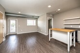 This well-designed single-floor unit offers a thoughtful layout with modern finishes and a neutral color palette throughout. The open-concept kitchen and living area serves as the heart of the space, featuring wood-look plank flooring, recessed lighting, and exposed ductwork that adds an industrial touch. The kitchen is equipped with light wood cabinetry, stainless steel countertops, black appliances including a range, dishwasher, and refrigerator, a single-basin sink, and open floating shelves for additional storage. A mobile butcher block island provides flexible workspace and flows naturally into the open living area.

The bedrooms are carpeted for comfort and each includes access to a walk-in closet outfitted with wire shelving and hanging rods, providing generous storage capacity. The unit features two bathrooms, both finished with classic white hexagonal tile flooring. The primary bathroom includes a wide vanity with a white countertop, a large mirror, and a soaking tub, while the secondary bathroom is compact and functional with its own closet access. A set of double doors with light wood veneer opens to additional space, and a textured ceiling and large double-paned windows allow natural light to fill the common areas.