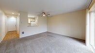 Located at 4900 SW Greensboro Way in Beaverton, Oregon, this well-appointed one-bedroom, one-bathroom residence offers a comfortable and functional layout across a single floor. The living room is a welcoming space featuring plush carpeting, a ceiling fan with light fixture, and large sliding glass doors that open onto a private balcony. The balcony overlooks a landscaped green area with mature trees, providing a serene outdoor retreat. An open pass-through connects the living area to the kitchen, which features wood-toned cabinetry and under-cabinet lighting, creating an efficient and connected layout. The hallway transitions between living and private spaces with warm hardwood-style flooring, and includes a closet for additional storage. The bedroom is a quiet, carpeted retreat with a large window dressed with vertical blinds, a baseboard heater, and a full-width sliding closet. The full bathroom offers a single-sink vanity with wood-trimmed cabinetry, a large mirror, and a tub-shower combination with tile surround set on hardwood-style flooring. A dedicated laundry area with an in-unit washer and overhead shelving adds everyday convenience. This thoughtfully arranged home delivers practical living in a peaceful Beaverton community.