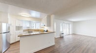 This single-floor residence offers 2 bedrooms and 2 bathrooms thoughtfully arranged across a comfortable and functional layout. The open-concept kitchen and living area serves as the heart of the home, where the kitchen features white shaker-style cabinetry, granite-look countertops, a stainless steel appliance suite including a refrigerator, electric range, and dishwasher, and a peninsula that provides additional prep space and naturally separates the kitchen from the living area. A window above the sink brings in natural light, while the adjoining living room extends toward sliding glass doors that further brighten the space. Rich wood-style flooring runs throughout the main living areas, adding warmth and continuity. The spacious primary bedroom offers a generous footprint with a wide window that frames outdoor greenery and provides ample natural light. The bathrooms are clean and functional, featuring white vanity cabinetry, a window for natural ventilation, and wood-style flooring. A hallway connects the private bedroom and bathroom areas to the main living spaces. The interior is finished with crisp white walls and textured ceilings, creating a bright and neutral backdrop. The overall ambiance is clean, modern, and move-in ready.