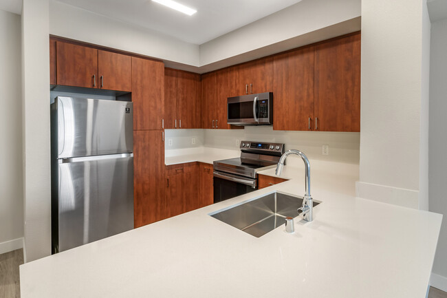 Renovated Package I kitchen with stainless steel appliances, white quartz countertops, cherry cabinetry, and hard surface flooring - Avalon Union City