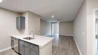 This contemporary 730 square foot apartment in Towson, Maryland offers a blend of comfort and functionality. The single-floor layout comprises one bedroom, one bathroom, and an open-concept living area. The kitchen is a highlight, featuring sleek gray cabinetry, stainless steel appliances, and quartz countertops. It seamlessly integrates with the living space, creating an ideal environment for both relaxation and entertainment.

The bathroom boasts a modern design with a white tiled shower/tub combination and chrome fixtures. The bedroom, measuring 170 square feet, provides ample space and is complemented by a closet for storage. Throughout the apartment, wood-look vinyl flooring adds warmth and durability.

Large windows in the living area and bedroom flood the space with natural light and offer picturesque views of the surrounding area. The neutral color palette of the walls creates a versatile canvas for personal decor. Ceiling-mounted lighting fixtures and a ceiling fan in the bedroom enhance the overall ambiance.

Located at 960 Southerly Road, this apartment combines contemporary living with the charm of Towson, making it an attractive option for those seeking a modern, low-maintenance lifestyle in a prime location.