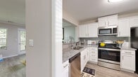Located in Sandy Springs, GA, this well-appointed 2-bedroom, 1-bathroom home offers a thoughtfully designed single-floor layout with a comfortable sense of space throughout. The kitchen is a standout feature, showcasing crisp white shaker cabinetry, granite countertops, a classic subway tile backsplash, and a full suite of stainless steel appliances including a dishwasher, range, microwave, and refrigerator, all set atop durable wood-look flooring. The adjacent dining area features crown molding, wood-look flooring, and a sliding door that invites natural light into the space. The living room is bright and welcoming, with large windows offering lush, tree-lined views and wood-look flooring throughout. The generously sized primary bedroom features plush carpeting, a walk-in closet with wire shelving, and direct access to the bathroom. The second bedroom is equally comfortable with carpeted floors and a closet. The bathroom is elegantly finished with granite countertops, a large vanity mirror, and a shower-tub combination. Two dedicated closets provide ample storage, completing this well-rounded and move-in-ready home.