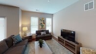 This single-floor unit offers a thoughtfully designed layout that balances comfort and modern style. The open-concept living and dining area features warm hardwood flooring, neutral-toned walls, and large windows fitted with white blinds that allow abundant natural light to fill the space. A ceiling fan with integrated lighting adds both function and style to the living room, which flows seamlessly into a dedicated dining area.

The kitchen is a standout feature, equipped with rich dark-stained cabinetry, light quartz countertops, and a full suite of stainless steel appliances including a gas range, built-in microwave, and refrigerator. A subway tile backsplash adds texture, while a central island with an integrated sink and bar seating provides additional workspace and casual dining options. Pendant lighting above the island enhances the contemporary aesthetic.

The bedroom is generously proportioned, offering plush carpeting, a ceiling fan, and a wide window that invites natural light. It connects directly to a walk-in closet, providing ample storage. The bathroom features hardwood-style flooring, dark vanity cabinetry, and clean, minimalist finishes. Throughout the unit, the cohesive neutral color palette and modern fixtures create a calm, functional living environment.