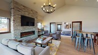 The Insignia Apartment Homes clubhouse at 1060 Insignia Loop in Bremerton, WA, is a thoughtfully designed single-floor amenity space that serves as a social and recreational hub for residents. The welcoming entry foyer greets visitors with vaulted ceilings, tile flooring, branded area rugs, and a set of decorative barn-style sliding doors with etched glass panels that open into the main lounge.

The central lounge is an impressive gathering space featuring soaring ceilings, warm hardwood flooring, and a dramatic floor-to-ceiling stacked-stone accent wall housing a linear electric fireplace and wall-mounted television. A rustic wood coffee table anchors the seating area, which is illuminated by a statement chandelier overhead. The space flows naturally into a dining nook with bar-height seating.

The fully equipped kitchen showcases dark cabinetry with sleek hardware, granite countertops, a stacked-stone tile backsplash, and full stainless steel appliances. An adjacent recreation area accommodates a foosball table, adding a casual, playful element to the space. Cozy seating alcoves with natural window light offer quieter retreats.

The fitness center is well-appointed with treadmills, ellipticals, a stationary bike, free weights, and full-wall mirrors, complemented by ceiling fans and ample natural light. A hallway corridor with dual water fountains connects the various amenity areas efficiently throughout the building.