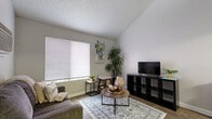Located at 1830 Bandera Road in San Antonio, Texas, this two-story, 2-bedroom, 1-bathroom home offers a practical and well-organized layout split evenly across two floors. The main level features a welcoming living room with wood-look flooring, vaulted ceilings, a large window that invites natural light, and a wall-mounted AC unit. The kitchen is efficiently designed with a peninsula breakfast bar seating two, white quartz-style countertops, gray upper cabinetry, black appliances including a range and refrigerator, and wood-look flooring that ties the space together cohesively. A full bathroom on the main level includes a tub/shower combination and a vanity with a light countertop. Upstairs, the primary bedroom features a dramatic sloped ceiling with a skylight that fills the room with natural light, along with carpet flooring and a wall-mounted AC unit. The second bedroom offers carpet flooring and neutral gray walls with a textured ceiling. A closet and hallway complete the upper level. Throughout the home, a neutral color palette of whites and grays provides a clean, modern aesthetic, while the staircase connects both levels seamlessly within the compact yet functional footprint.