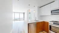 This contemporary apartment, located at 399 Fremont St in San Francisco, offers a sophisticated urban living experience. The 790 square foot space is efficiently designed with three bedrooms, including a primary bedroom of 140 square feet, and two bathrooms. The open-concept layout maximizes the use of space, creating a seamless flow between rooms.

The apartment boasts floor-to-ceiling windows that flood the interior with natural light and provide stunning panoramic views of the city skyline and San Francisco Bay. The living area features light-colored hardwood flooring, enhancing the sense of spaciousness and complementing the modern aesthetic.

The kitchen is a highlight, with its sleek design incorporating white upper cabinets and warm wood lower cabinets. High-end stainless steel appliances, including a gas range and side-by-side refrigerator, cater to culinary enthusiasts. A large kitchen island with a built-in sink serves as both a practical workspace and a casual dining area.

The bathrooms are elegantly appointed, featuring clean lines and contemporary fixtures. One bathroom includes a spacious bathtub, while the other offers a glass-enclosed shower, both finished with neutral-toned tiles for a spa-like ambiance.

Built-in closets in the bedrooms and hallway provide ample storage space. The apartment's overall design emphasizes a minimalist approach with its white walls and uncluttered spaces, creating a canvas for personalization while maintaining a sophisticated urban feel.