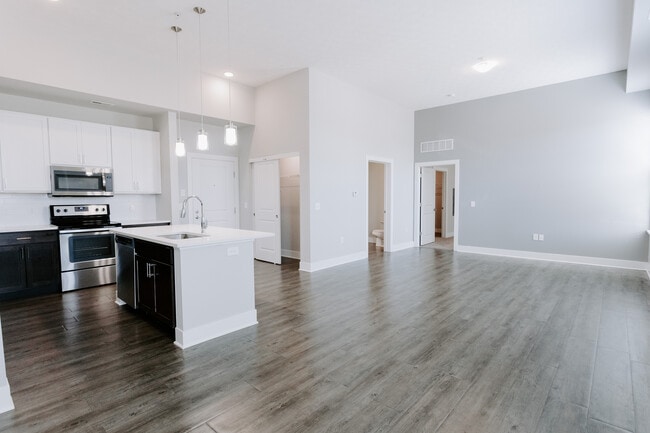 Experimente la vida moderna en esta elegante cocina de planta abierta y amplia sala de estar. - The Landon at New Albany Park