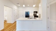 Located at 165 E Wright St in Winder, GA, this well-appointed two-bedroom, two-bathroom residence offers a thoughtfully designed single-level layout. Light hardwood flooring flows consistently throughout the entire unit, creating a cohesive and clean aesthetic.

The kitchen serves as a central highlight, featuring crisp white shaker-style cabinetry extending to the ceiling, marble-look countertops, and a suite of black stainless steel appliances including a refrigerator, gas range, and over-the-range microwave. A peninsula with a double basin sink and pendant lighting above provides both additional prep space and a natural division between the kitchen and living areas.

Both bedrooms are bright and well-proportioned, each equipped with ceiling fans and windows that invite natural light and outdoor views. The primary bedroom includes access to a dedicated closet with built-in shelving for organized storage. Additional closets throughout the unit provide ample storage solutions.

The two bathrooms are finished consistently with marble-look vanity countertops, white cabinetry, hardwood-style flooring, and full tub-shower combinations outfitted with brushed nickel grab bars and curtain rods. The overall palette of white walls and warm flooring gives the home a bright, modern, and move-in-ready feel.