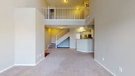 Located in Saint Petersburg, Florida, this two-story residence offers a well-designed layout that balances open communal spaces with private upper-level accommodations. The living area immediately impresses with soaring double-height ceilings and a carpeted floor, creating an expansive, airy atmosphere. Large French doors flood the space with natural light and provide outdoor access, while a white-railed staircase and upper-level balcony add architectural interest and visual depth to the interior.

The kitchen is efficiently laid out in a galley style, featuring stainless steel appliances including a full-sized refrigerator and range, white cabinetry, a light tile backsplash, and rich hardwood-style flooring. A breakfast bar peninsula connects the kitchen to the living area, making it ideal for casual dining or entertaining. Hardwood-style flooring continues throughout the kitchen and bathrooms, providing a warm contrast to the plush carpeting found in the living and bedroom areas.

The bathrooms are finished with white vanity cabinetry, clean countertops, large mirrors, and tiled shower-tub combinations. Bedrooms are generously proportioned, carpeted, and well-lit by natural light through blinded windows. The primary bedroom features a connected en-suite bathroom, adding a layer of privacy and convenience. Overall, the home presents a clean, neutral palette throughout.