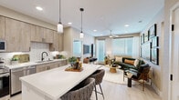 This thoughtfully designed 2-bedroom, 2-bathroom single-floor residence offers a cohesive blend of modern aesthetics and functional living. The open-concept kitchen and living area serves as the heart of the home, featuring warm wood-tone cabinetry, white quartz countertops, a subway tile backsplash, stainless steel appliances, and a central island with seating for two — illuminated by stylish pendant lighting. The living area flows seamlessly from the kitchen, bathed in natural light from large windows dressed with sheer curtains and blinds, and is topped with a ceiling fan for added comfort. Light wood-tone flooring runs throughout, tying the spaces together. The primary bedroom features a bold geometric accent wall, access to a dedicated en-suite bathroom with textured wallcovering, a wood vanity, white quartz countertop, matte black fixtures, and a walk-in closet. The second bedroom showcases a rich teal accent wall and an integrated closet with built-in shelving. The second bathroom continues the home's design language with vibrant, artistic wallpaper, a lit vanity mirror, and matte black hardware. A hallway connects all areas efficiently, completing this well-organized and visually dynamic residence.